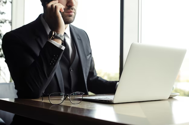 empresario hablando por telefono sentado en un escritorio frente a una portatil